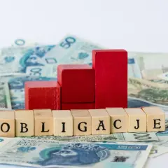 Drewniane klocki z napisem "OBLIGACJE" na tle polskich banknotów. Czy można kupić obligacje bez konta w PKO?