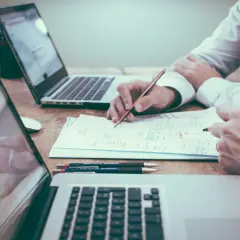 Dwie osoby analizują dokumenty przy laptopach. To przykład, jak nakłady inwestycyjne co to, mogą być omawiane w praktyce.
