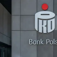 Logo PKO Banku Polskiego na szarej ścianie. Dowiedz się, jak kupić obligacje skarbowe w PKO BP.