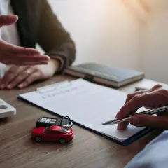 Podpisanie umowy leasingu operacyjnego. Na stole leżą kluczyki do auta, zabawkowy samochód i kalkulator.