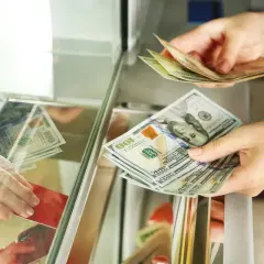 Ręce przekazują sobie banknoty dolarowe. Czy można kupić walutę w NBP? Tutaj widzimy wymianę pieniędzy.