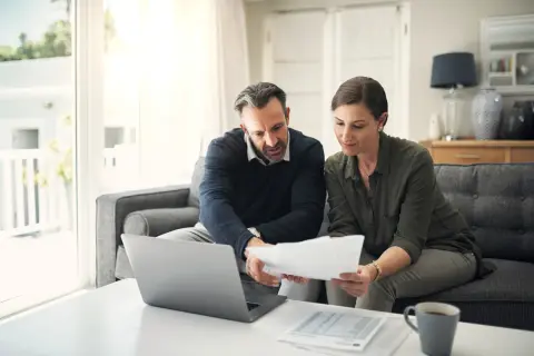 Para, analizując dokumenty i laptop, szuka odpowiedzi, gdzie najłatwiej dostać kredyt konsolidacyjny.