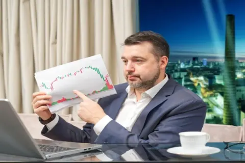 Mężczyzna analizuje wykresy, zastanawiając się, jak zarobić na giełdzie 200 złoty dziennie.