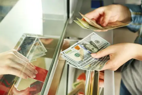Ręce przekazują sobie banknoty dolarowe. Czy można kupić walutę w NBP? Tutaj widzimy wymianę pieniędzy.
