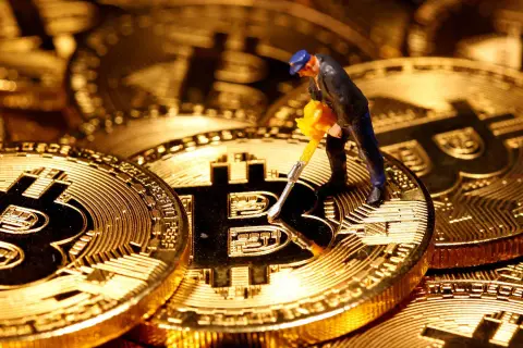 Figurka górnika z kilofem na złotych monetach Bitcoin. Cena kryptowaluty zależy od wielu czynników, w tym od popytu i podaży.