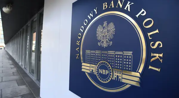 Złote godło i napis "NARODOWY BANK POLSKI" na granatowej tablicy, symbolizujące stabilność finansową kraju.