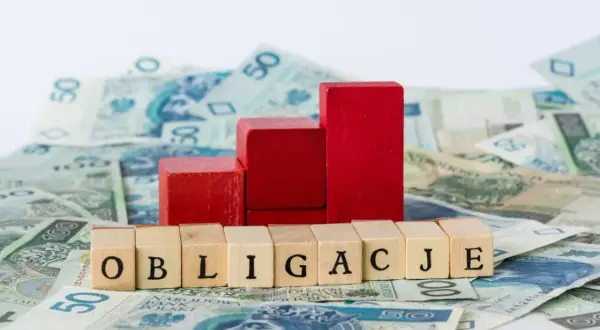 Drewniane klocki z napisem "OBLIGACJE" na tle polskich banknotów. Czy można kupić obligacje bez konta w PKO?