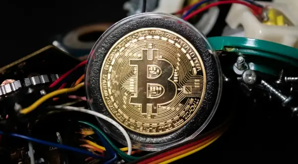 Złoty Bitcoin otoczony przewodami i elementami elektronicznymi, symbolizujący, jak działa koparka kryptowaluty.