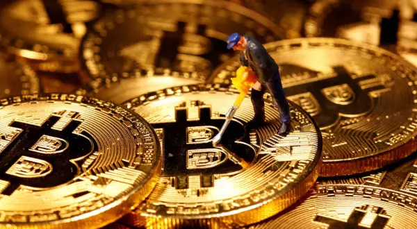 Figurka górnika z kilofem na złotych monetach Bitcoin. Cena kryptowaluty zależy od wielu czynników, w tym od popytu i podaży.
