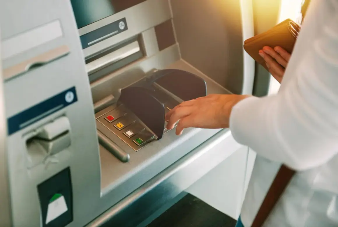 Dłoń wpisuje PIN przy bankomacie, z nadzieją, że nie zniknęły pieniądze z konta.
