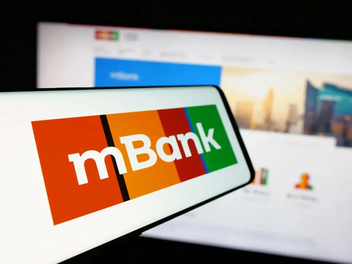 Logo mBank na ekranie smartfona, obok ekran komputera z widokiem na miasto. Szukasz informacji, jak spłacić kredyt odnawialny mBank?