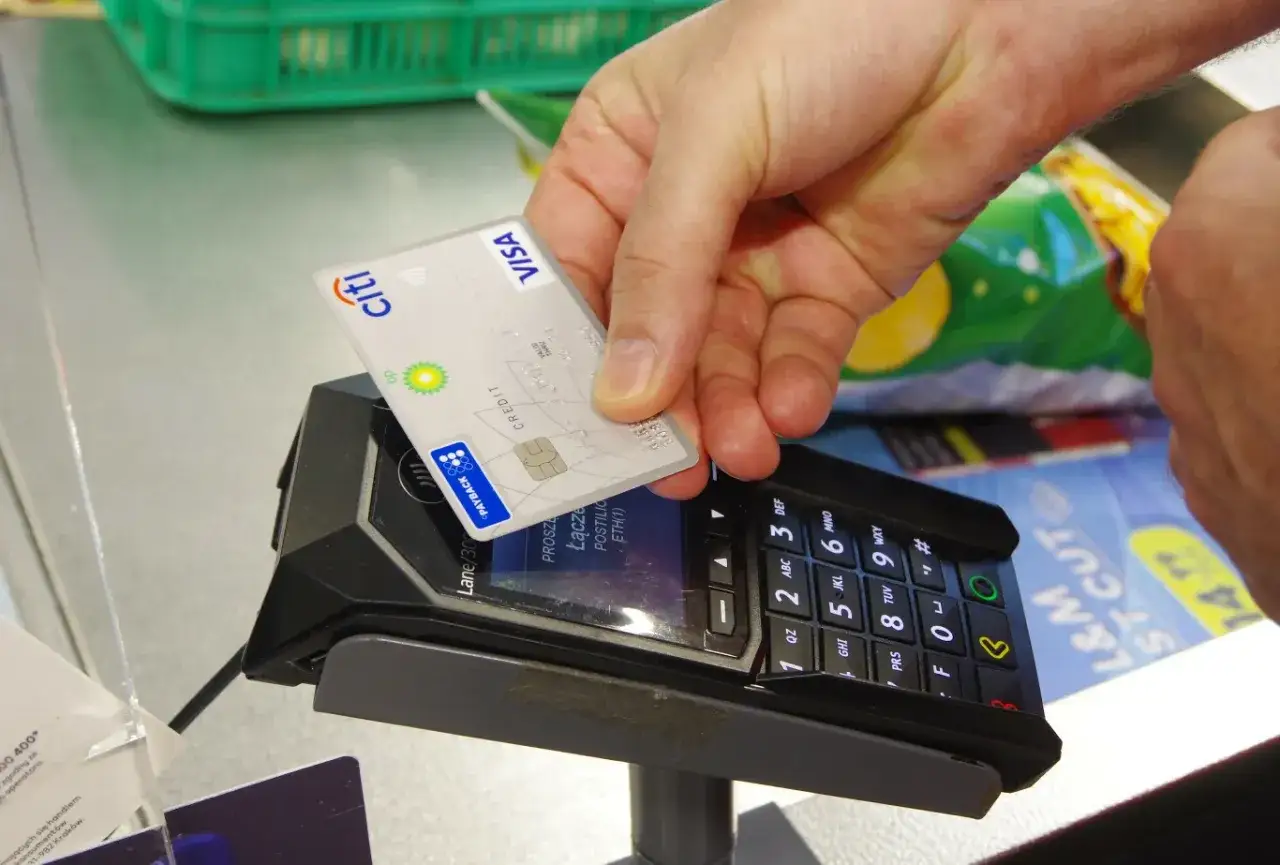 Zbliżanie karty debetowej Citi z logo Visa do terminala płatniczego.