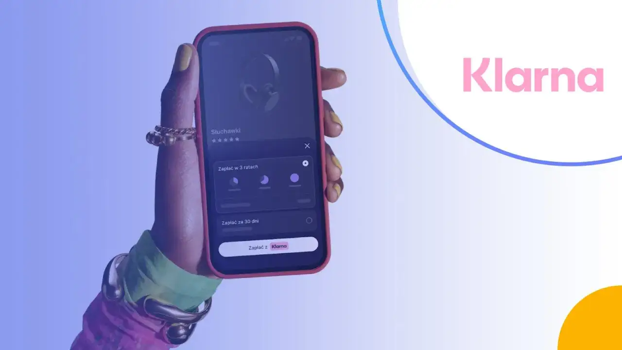 Dłoń trzyma telefon z aplikacją Klarna, pokazującą opcje płatności za słuchawki w ratach lub za 30 dni. Klarna co to? To wygodne zakupy.
