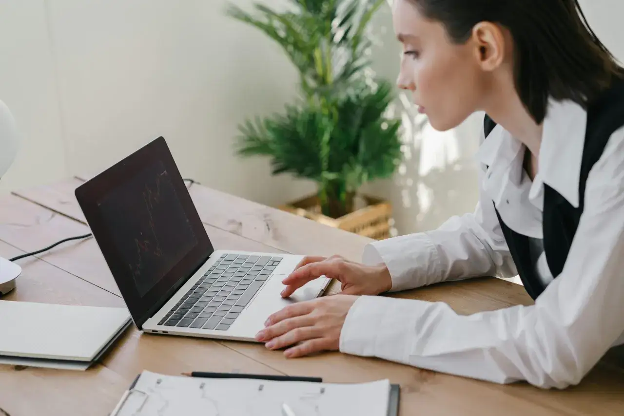 Kobieta analizuje wykresy na laptopie, zaniepokojona, że zniknęły pieniądze z konta.