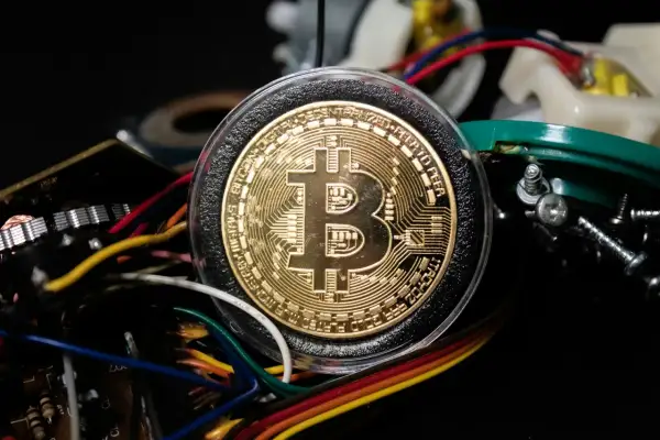 Złoty Bitcoin otoczony przewodami i elementami elektronicznymi, symbolizujący, jak działa koparka kryptowaluty.