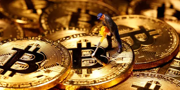 Figurka górnika z kilofem na złotych monetach Bitcoin. Cena kryptowaluty zależy od wielu czynników, w tym od popytu i podaży.